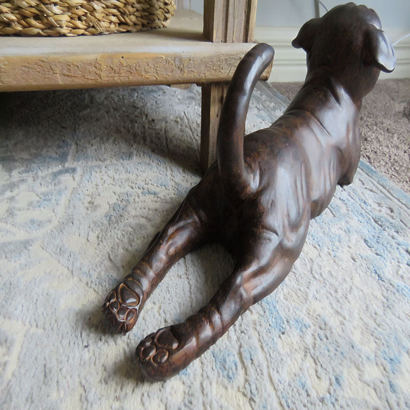 Back view of stretching pug figurine showing curled tail and paws